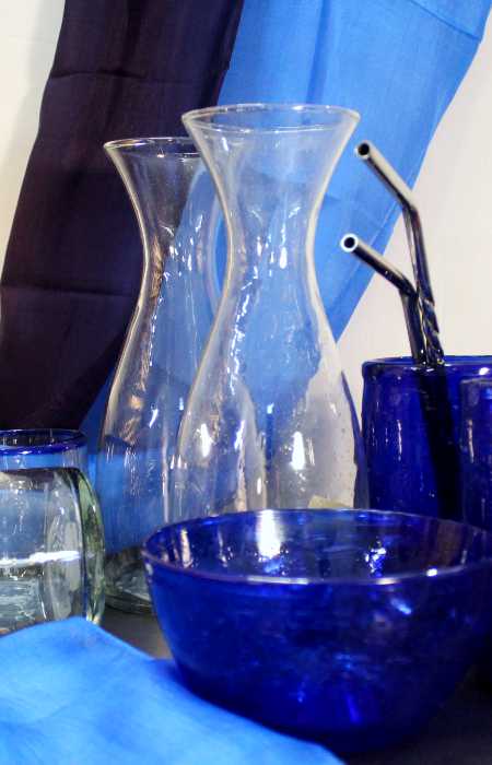 Glaskaraffen und blaue Glasschalen vor blauen Tüchern