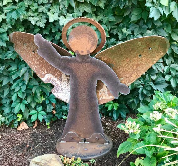 Engel aus Eisenteilen vom Schrott in einem Garten vor grünem Hintergrund